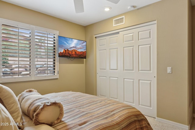 carpeted bedroom with a ceiling fan, baseboards, visible vents, and a closet