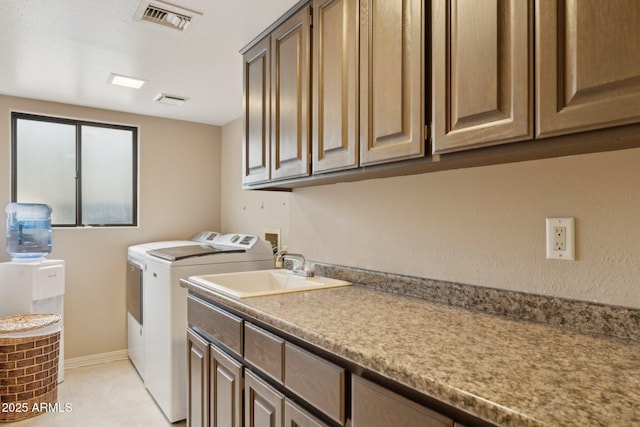 clothes washing area with washing machine and clothes dryer, visible vents, baseboards, cabinet space, and a sink