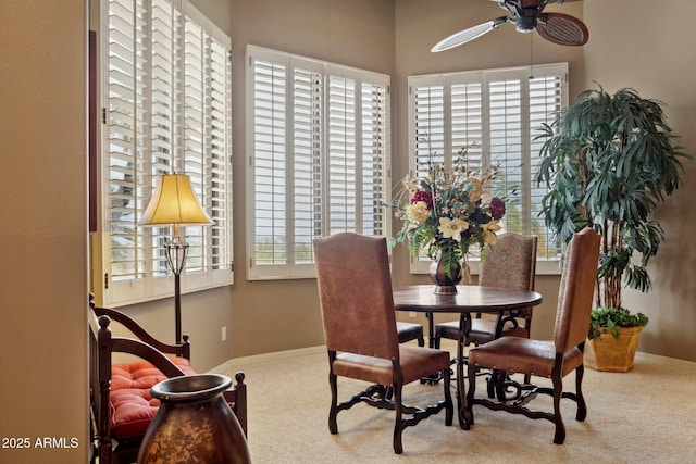 carpeted dining area featuring a healthy amount of sunlight, a ceiling fan, and baseboards