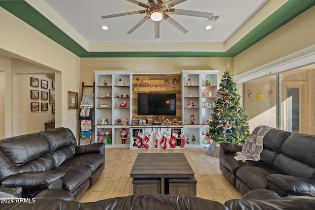 living room with a raised ceiling, light hardwood / wood-style flooring, and ceiling fan