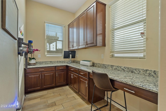 interior space featuring light hardwood / wood-style floors, light stone counters, and built in desk