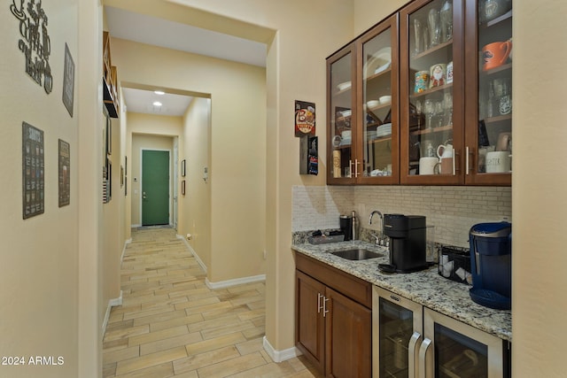 bar featuring light stone countertops, decorative backsplash, light hardwood / wood-style floors, and sink