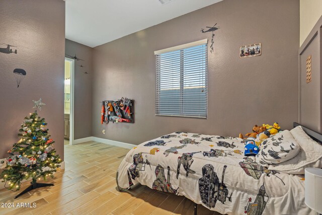 bedroom featuring connected bathroom and light hardwood / wood-style floors