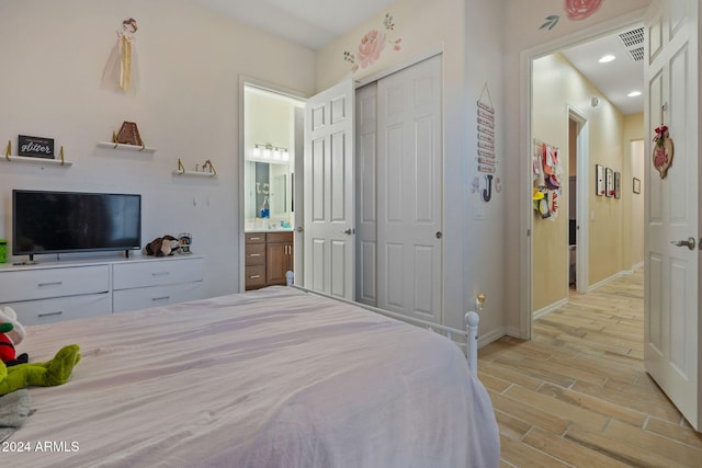 bedroom featuring light hardwood / wood-style floors, a closet, and ensuite bath