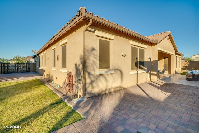 back of property with a lawn and a patio area