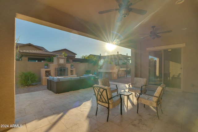 patio terrace at dusk featuring an outdoor living space with a fireplace and ceiling fan