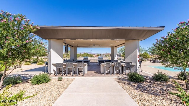 view of patio / terrace featuring an outdoor pool, a ceiling fan, area for grilling, outdoor dry bar, and outdoor dining space