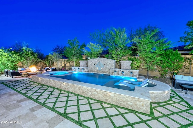 pool at night with a patio, an in ground hot tub, and outdoor lounge area