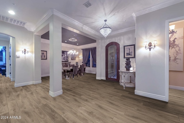 foyer with ornamental molding, hardwood / wood-style flooring, and a chandelier