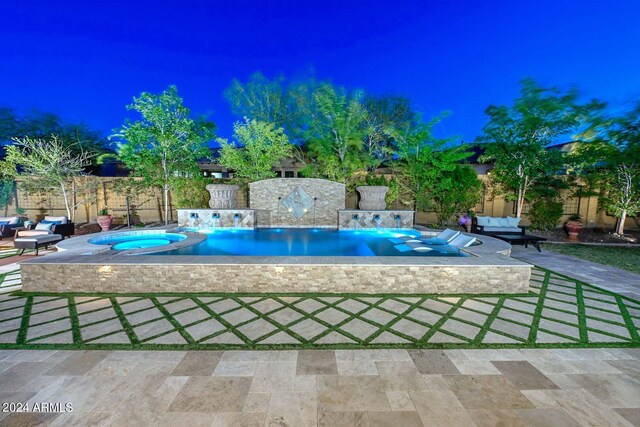 pool at twilight with an in ground hot tub and a patio area