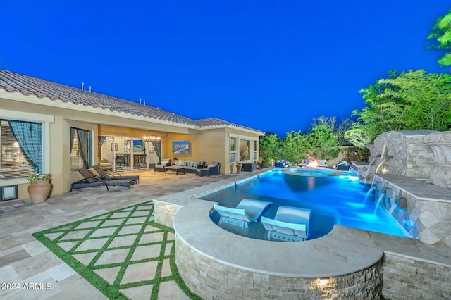 pool at night featuring an in ground hot tub, a patio, and pool water feature