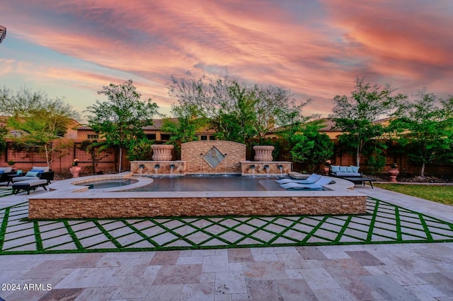 pool at dusk with a patio and an in ground hot tub