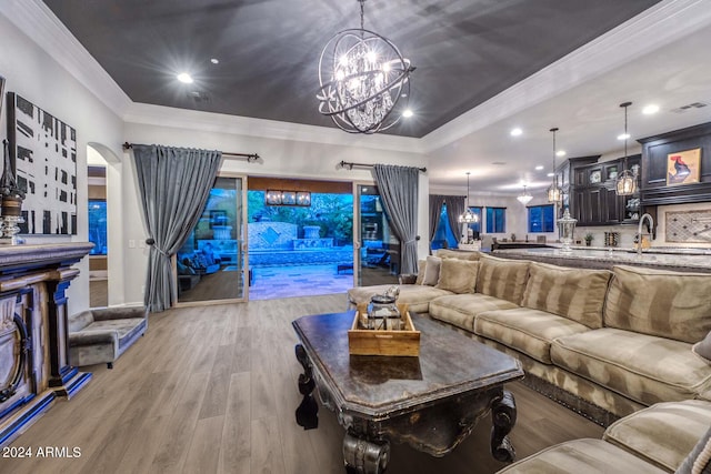 living room featuring crown molding, light hardwood / wood-style floors, and a notable chandelier