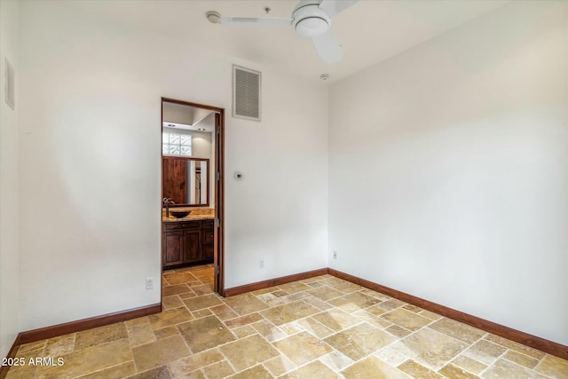 unfurnished room with stone tile floors, baseboards, a ceiling fan, and visible vents