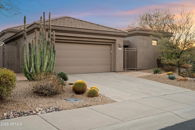 view of front of house with a garage, driveway, a tiled roof, and stucco siding