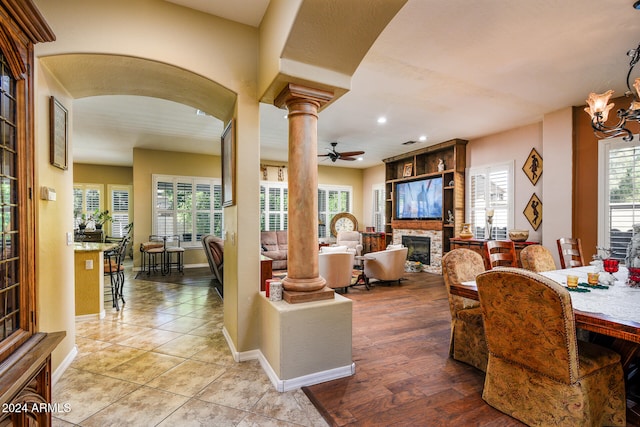 interior space with ceiling fan with notable chandelier, a fireplace, and a healthy amount of sunlight