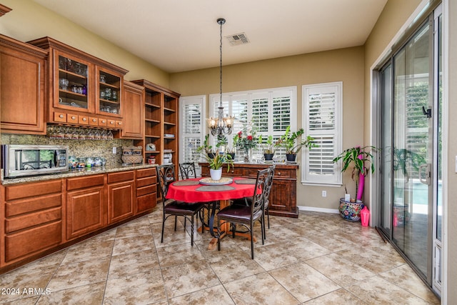 tiled dining space featuring a wealth of natural light and an inviting chandelier