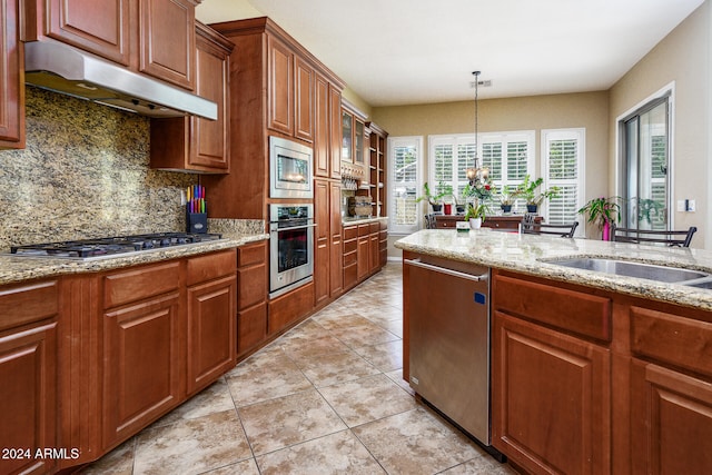 kitchen featuring decorative backsplash, appliances with stainless steel finishes, a chandelier, and light stone counters