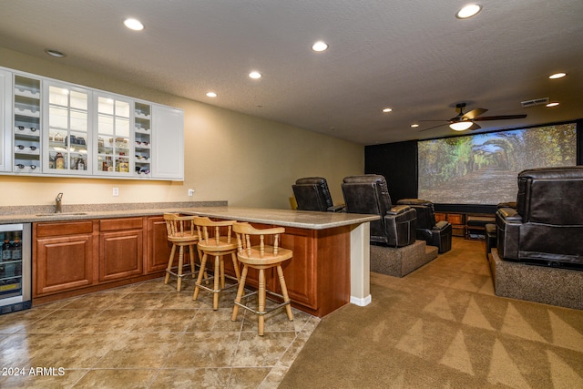 kitchen with wine cooler, a breakfast bar, kitchen peninsula, ceiling fan, and light colored carpet