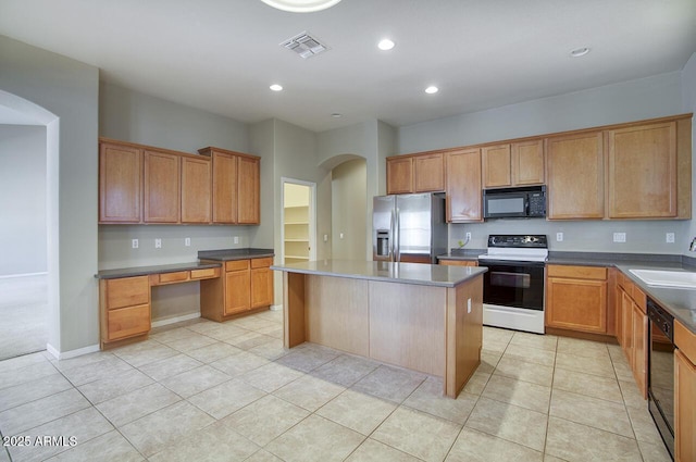 8068 W Carlota Ln, Peoria, AZ 85383 - kitchen with black appliances, arched walkways, a center island, built in study area, and light tile patterned flooring