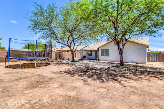 1858 S Ocotillo Dr, Apache Junction, AZ 85120 - back of house with a trampoline, a fenced backyard, stucco siding, and a patio area