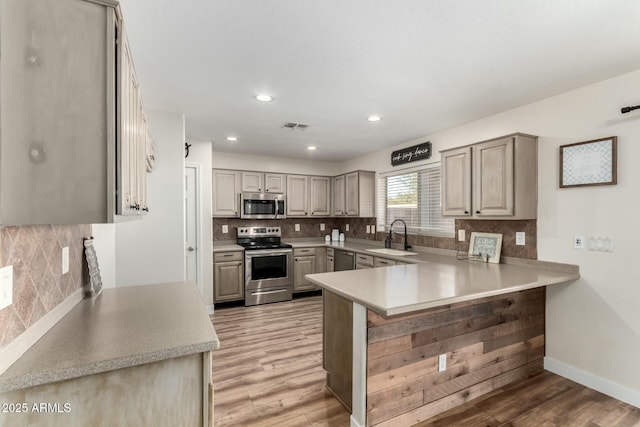 kitchen featuring gray cabinets, a breakfast bar, kitchen peninsula, sink, and stainless steel appliances