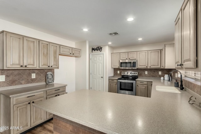 kitchen with sink, appliances with stainless steel finishes, kitchen peninsula, and tasteful backsplash