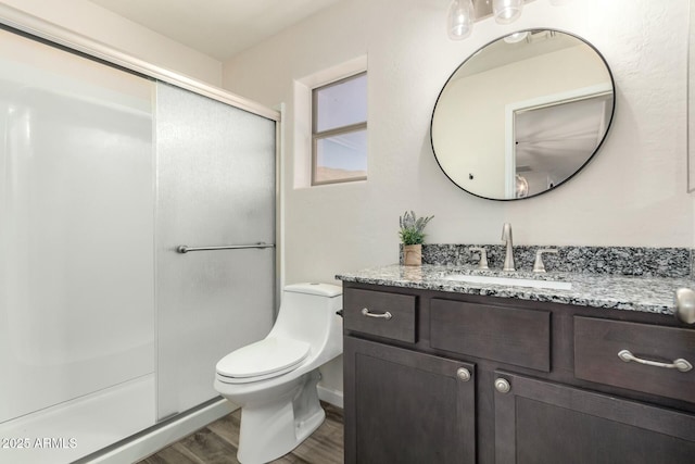 bathroom featuring hardwood / wood-style floors, toilet, a shower with door, and vanity