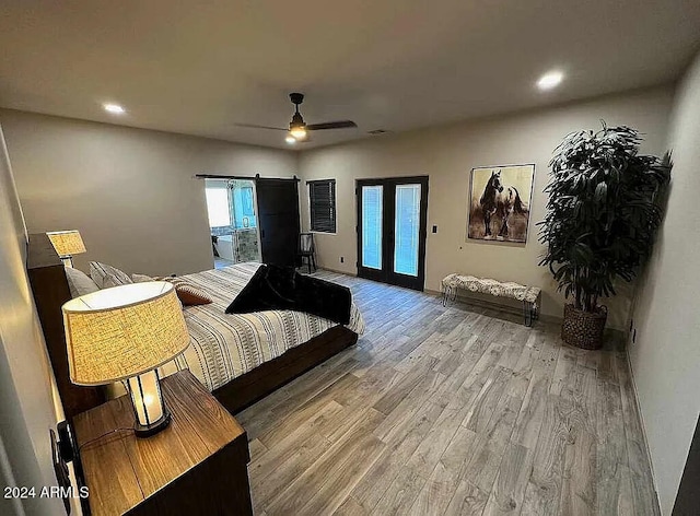 bedroom with french doors, ceiling fan, a barn door, access to exterior, and light hardwood / wood-style floors