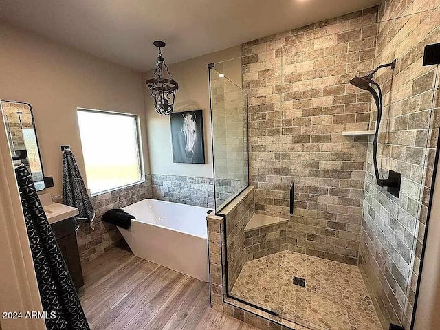 bathroom with a chandelier, plus walk in shower, and wood-type flooring