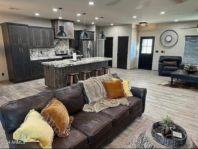 living room featuring light hardwood / wood-style flooring, ceiling fan, and sink