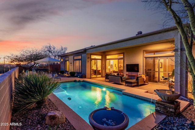 pool at dusk featuring an outdoor hangout area, pool water feature, and a patio area