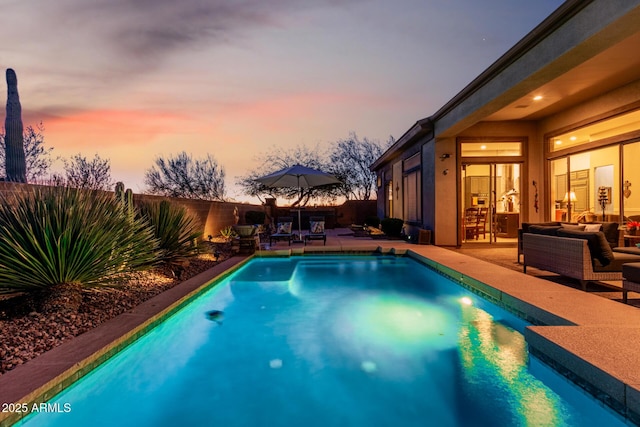 pool at dusk with an outdoor living space and a patio