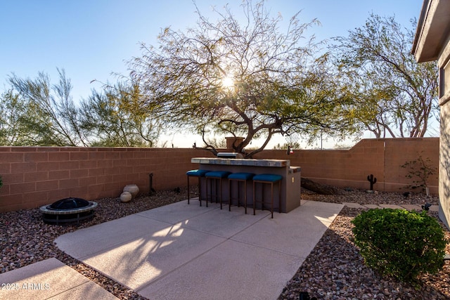 patio terrace at dusk with exterior bar and a fire pit