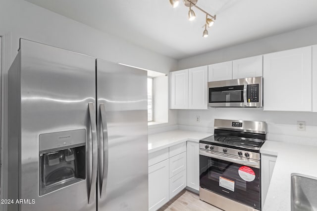 kitchen with white cabinets, stainless steel appliances, and light hardwood / wood-style flooring