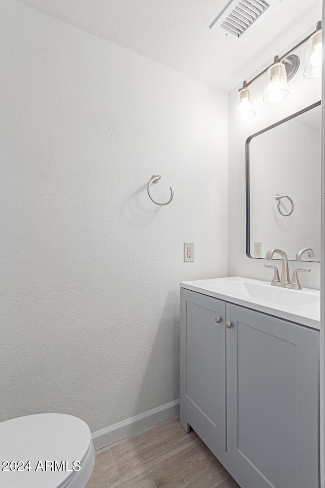 bathroom with hardwood / wood-style floors, vanity, and toilet