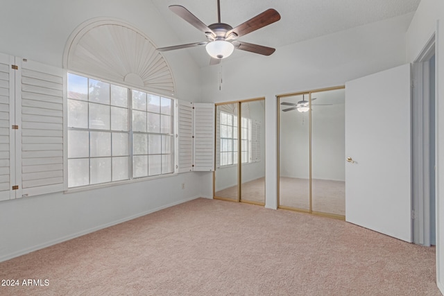 unfurnished bedroom with carpet, lofted ceiling, ceiling fan, and multiple closets