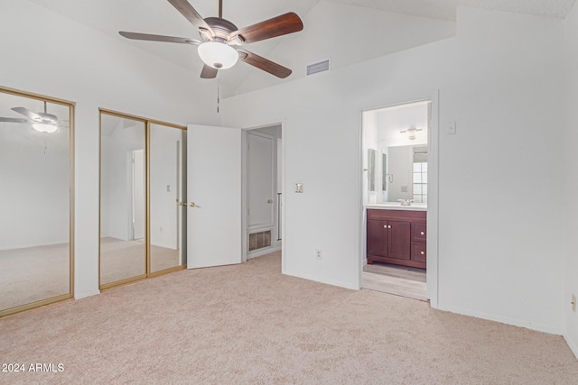 unfurnished bedroom with two closets, sink, ensuite bath, ceiling fan, and light colored carpet