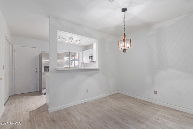 unfurnished room with light hardwood / wood-style flooring and an inviting chandelier