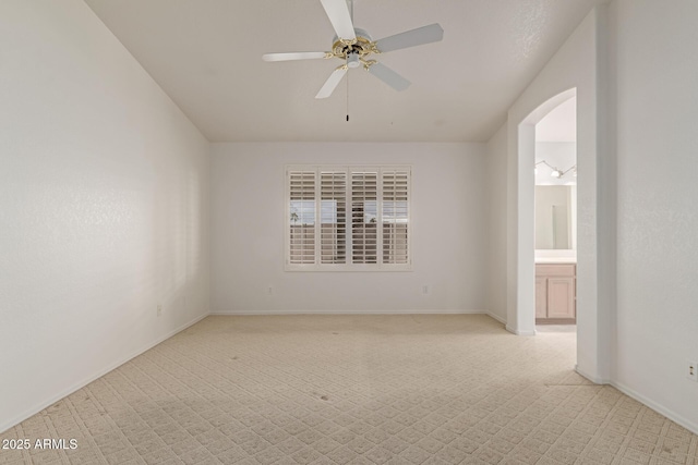 spare room with arched walkways, baseboards, and a ceiling fan