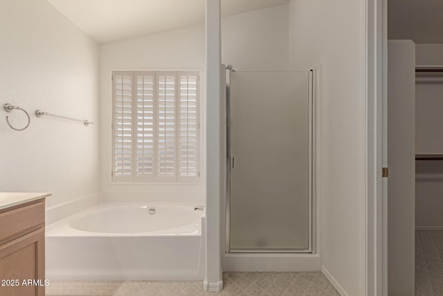 bathroom featuring vanity, a shower stall, a bath, and lofted ceiling