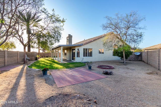 rear view of house with a patio area, stucco siding, a chimney, and a fenced backyard