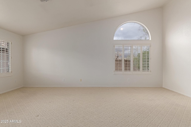 spare room featuring light colored carpet and baseboards