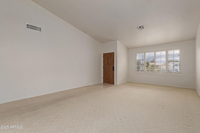 spare room featuring visible vents, lofted ceiling, and baseboards