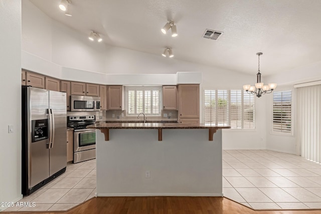 kitchen featuring visible vents, lofted ceiling, light tile patterned floors, a kitchen breakfast bar, and stainless steel appliances