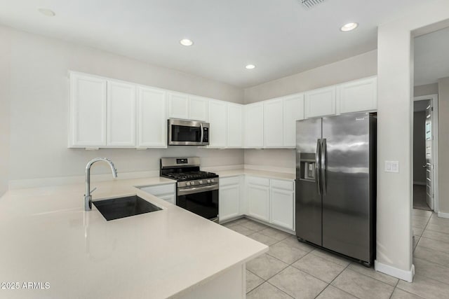 kitchen with appliances with stainless steel finishes, white cabinetry, sink, light tile patterned floors, and kitchen peninsula