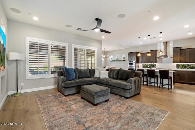 living area featuring visible vents, baseboards, light wood-style floors, recessed lighting, and ceiling fan with notable chandelier