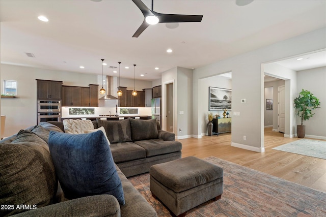 living area featuring light wood-type flooring, a ceiling fan, visible vents, and recessed lighting
