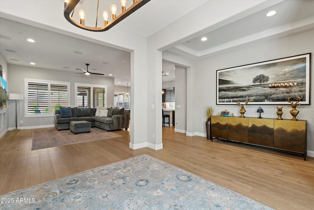 interior space featuring wood finished floors, ceiling fan with notable chandelier, baseboards, and recessed lighting