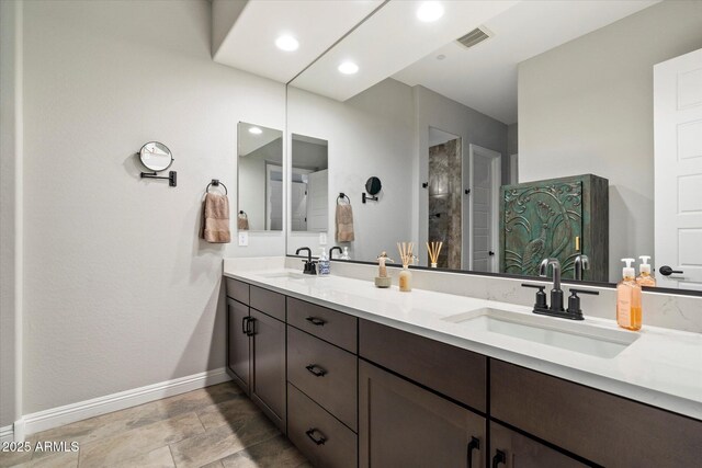 full bathroom with a tile shower, baseboards, a sink, and visible vents